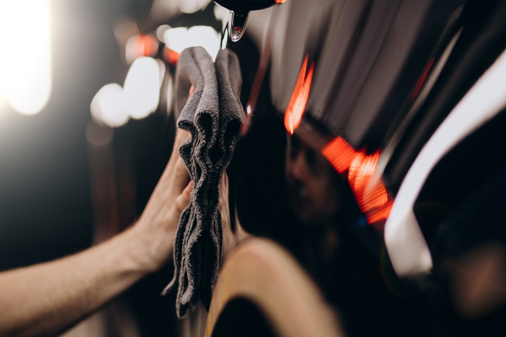 Detailer wiping ash and debris from a car's exterior