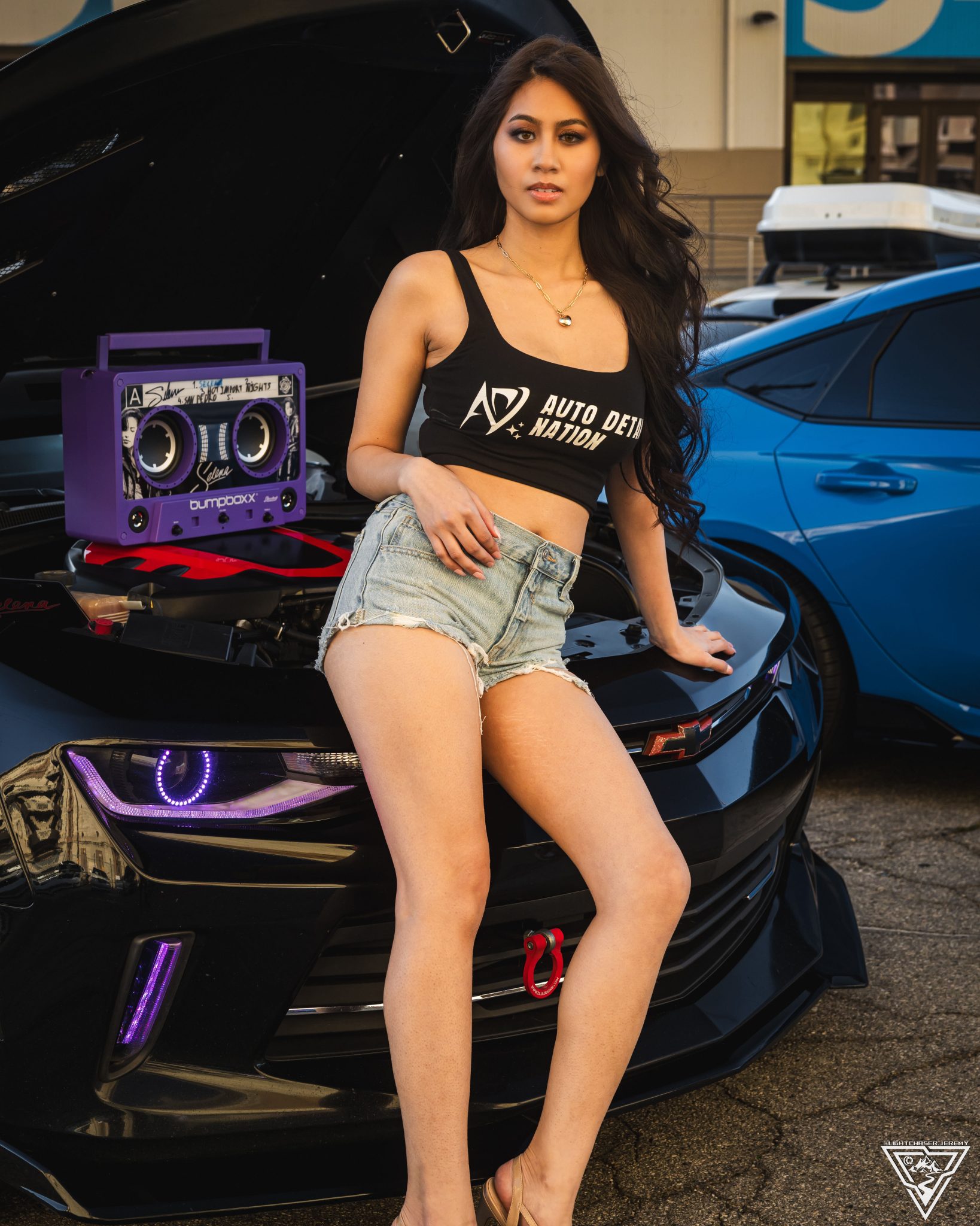 Joan Cruz seated on a show car with a boombox