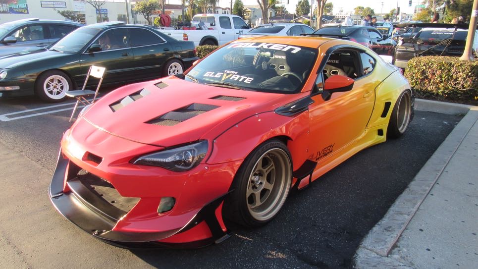 Orange and yellow widebody sports car with a custom wrap at the car meet
