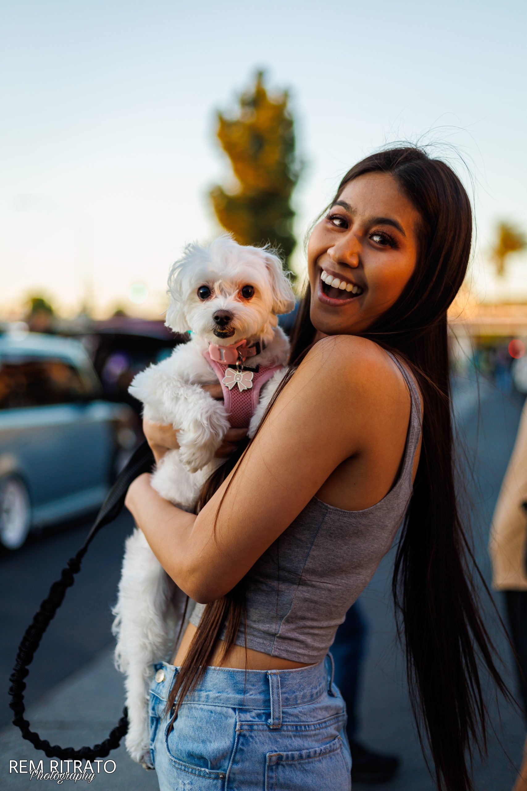 Joan Cruz smiling with a small white dog at the car meet