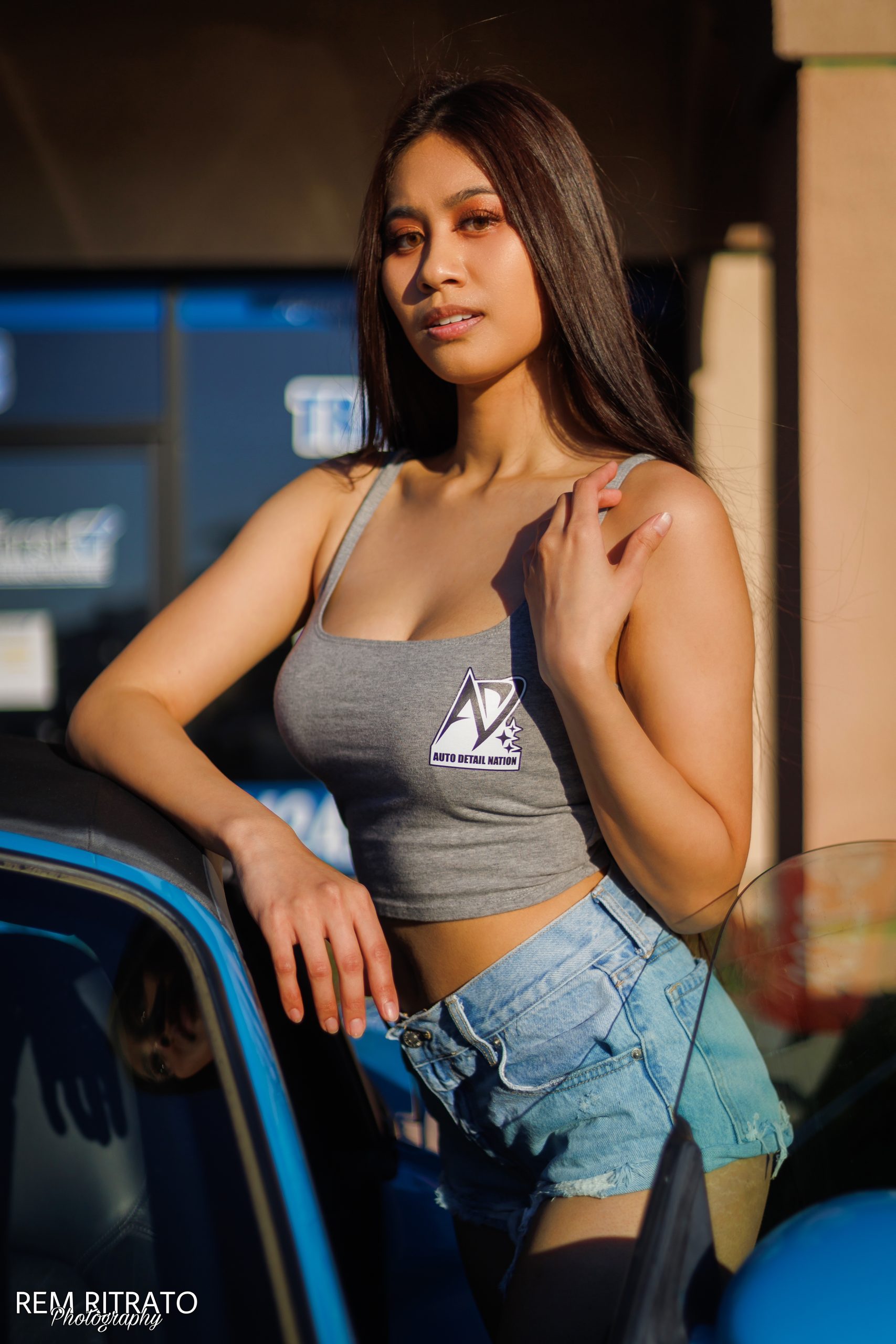Joan Cruz in an Auto Detail Nation top posing beside a car at the meet